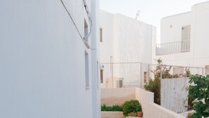 A narrow, white-walled alleyway with a stone pathway lined with potted plants. - Naousa Central House, Paros (Paros)