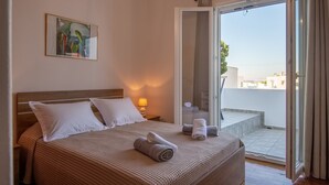 A hotel room with a bed, a painting on the wall, a lamp, and a view of the outside. - Naousa Central House, Paros (Paros)
