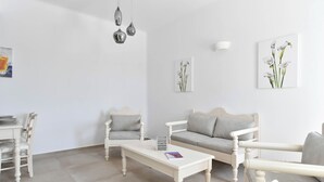 Uma sala de estar minimalista com um sofá branco, uma mesa de centro branca e uma mesa de jantar com cadeiras.