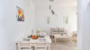 Uma área de refeições moderna com uma mesa branca posta para quatro pessoas, um sofá e uma mesa de centro.