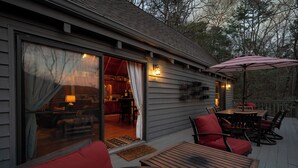 Eine Holzterrasse mit Gartenmöbeln, einem Esstisch und einem großen Sonnenschirm.