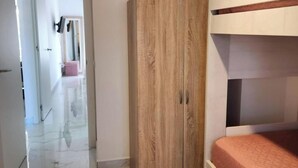 Een slaapkamer met een stapelbed, een houten garderobe en een marmeren vloer.