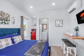 Ein Schlafzimmer mit Bett, Schreibtisch und einer Küchenzeile.