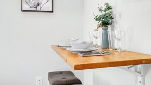 A dining table set with white plates, bowls, and glasses, a vase with green foliage, and a framed artwork on the wall. - Hill Country Views | Canyon Lake Retreat (Canyon Lake)