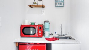 A small kitchenette with a red Galanz microwave, a teal coffee maker, a white mug, and a red oven mitts on the counter. - Hill Country Views | Canyon Lake Retreat (Canyon Lake)