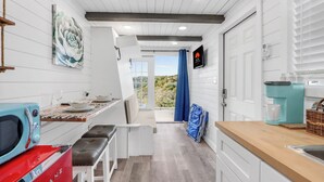 Una cocina moderna con armarios blancos, una estufa roja y una cafetera azul.