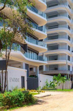 A multi-story building with balconies, a gated entrance, and a sign that reads 'EVOQUE.'