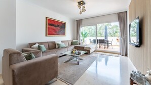 A modern living room with a sectional sofa, a glass coffee table, and a flat-screen TV. - Apartment in Elviria With Terrace, Marbella (Marbella)