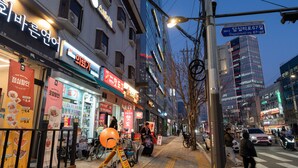 A street with various shops, a pedestrian crossing, and a tall building in the background. - STAYV Jang-an (Seoul)
