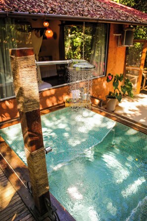 Ein Schwimmbad mit Holzterrasse, Glaseinfassung und einer Topfpflanze.