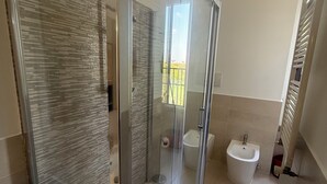 A modern bathroom with a glass shower enclosure, a bidet, and a toilet. - Nice newly renovated apartment with all amenities near the metro. (Milano)