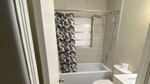 Un baño pequeño con ducha, inodoro y lavamanos.