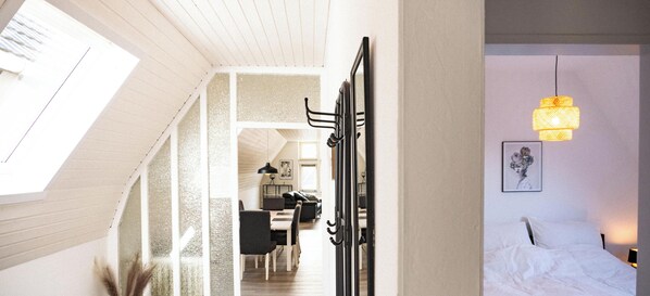 A modern interior with a staircase, a dining area, and a bed with a headboard.