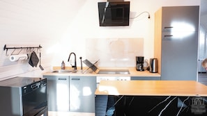 A modern kitchen with a dishwasher, sink, and coffee maker.