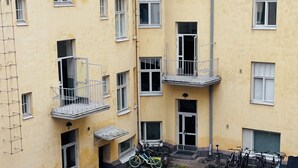 A multi-story yellow building with balconies, a courtyard with potted plants, and bicycles parked outside. - Peaceful Artsy Home Stay (Helsinki)