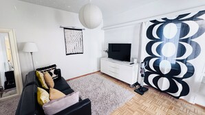 A modern living room with a sofa, TV, and decorative wall art. - Peaceful Artsy Home Stay (Helsinki)