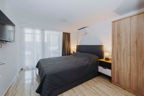 Ein Schlafzimmer mit Bett, Kleiderschrank, Fernseher und einem Fenster mit Vorhängen.