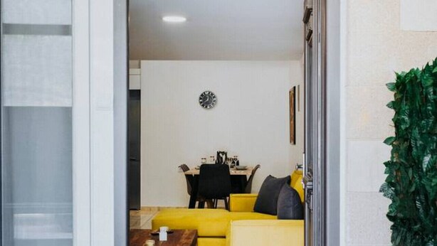 Un interior moderno con un sofá amarillo, una mesa de comedor y un reloj en la pared.