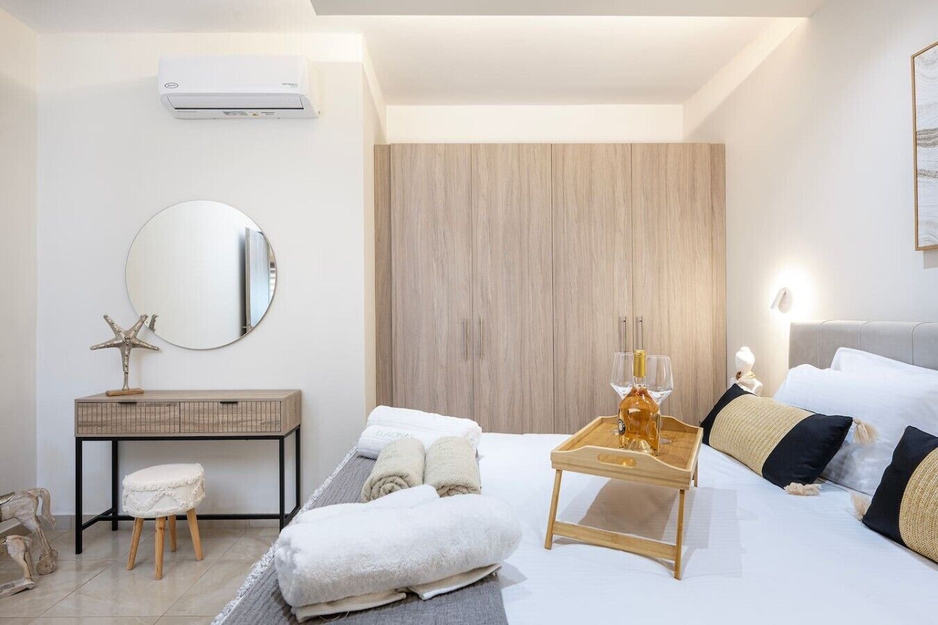 Een moderne hotelkamer met een bed, nachtkastje, spiegel en een houten garderobe.