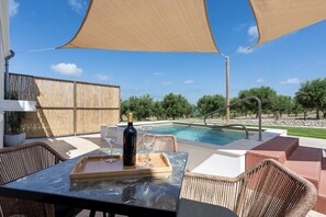 Ein Poolbereich mit Tisch, Stühlen, einer Weinflasche und einem Pool.