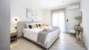 Ein modernes Schlafzimmer mit einem großen Bett, Nachttischen, einer Nachttischlampe, einer Wand-Klimaanlage und einer dekorativen Pferdeskulptur.