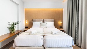 A double bed with a headboard, bedside tables, a potted plant, and a curtain.
