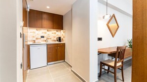 A compact kitchen with wooden cabinets, a built-in dishwasher, and a dining area with a wooden table and chair.