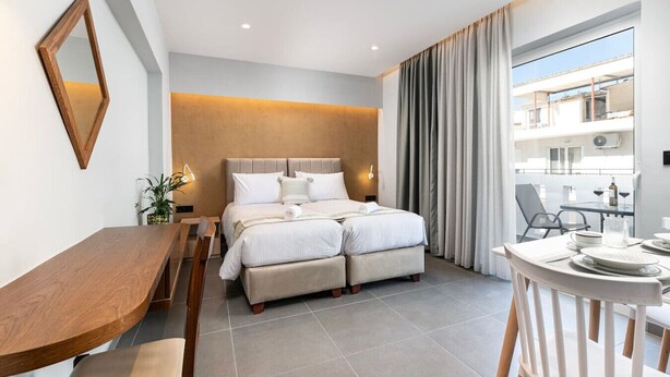 A modern hotel room with a bed, a desk, a chair, and a balcony with a view.