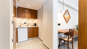 A compact kitchen with a dishwasher, wooden cabinets, and a tiled backsplash.