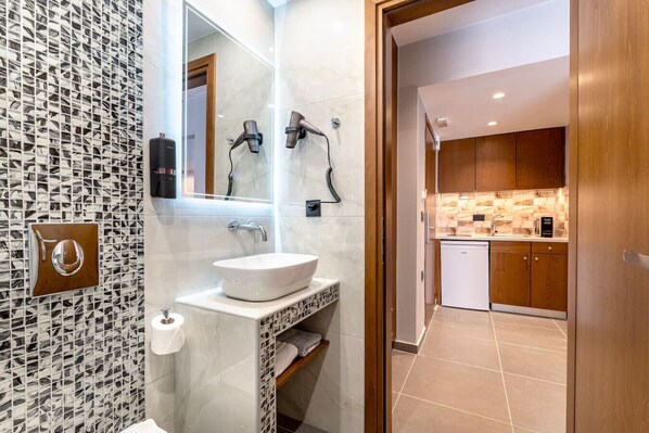 Un baño moderno con un lavamanos blanco, un espejo y un secador de pelo.