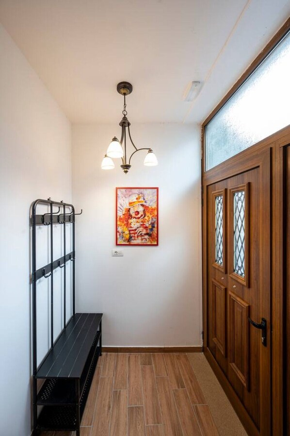 A hallway with a wooden door, a coat rack, a bench, and a ceiling light fixture.