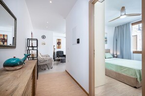 A hotel room with a bed, a desk, a chair, a mirror, and a window with curtains.