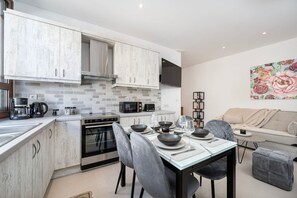 A modern kitchen with a dining area, featuring a built-in oven, microwave, and coffee maker.