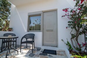A patio with two chairs, a table, a door, and a window. - Thines Studios : Studio A (Kampos)