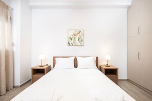 Ein Hotelzimmer mit einem großen Bett, zwei Nachttischen mit Lampen, einem Holz-Kopfteil, einem Wandbild und einem Kleiderschrank.