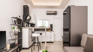 Une cuisine moderne avec des meubles blancs, un îlot central et un coin repas comprenant une table blanche et deux tabourets de bar.