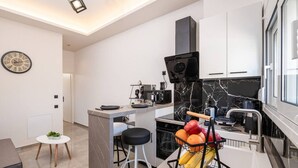 Une cuisine moderne avec un dosseret en marbre, une cuisinière encastrée et un panier de fruits posé sur le plan de travail.