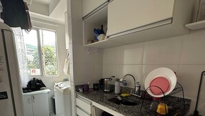 Eine Küche mit weißen Schränken, einer Granitabdeckung, einem Herd und einem Fenster mit Blick auf Grünflächen.