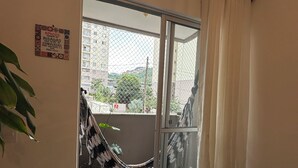 Ein Balkon mit einer Hängematte, einem Blumentopf und Blick auf Gebäude.