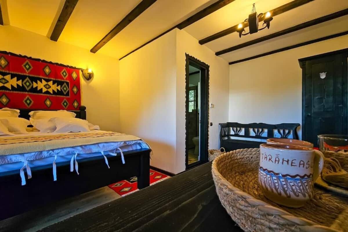 Una habitación con cama, una cesta tejida con una taza y una puerta con un espejo en forma de corazón.