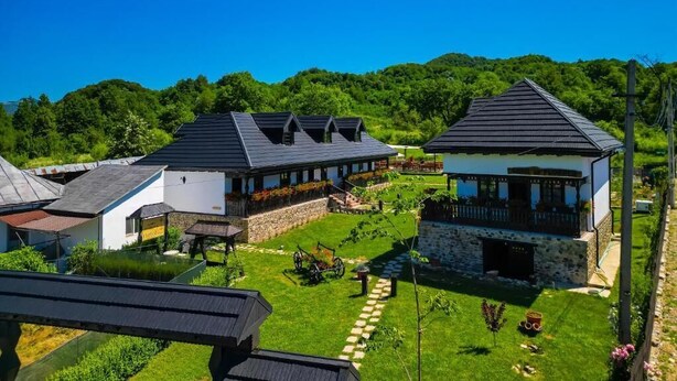 Uma área residencial com várias casas, um muro de pedra e céu claro.