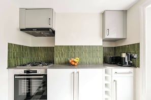 A modern kitchen with a gas stove, oven, and a coffee maker on the countertop. - The Notting Hill Blue Palace (Greater London)