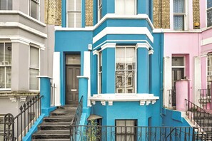 A multi-story building with a blue facade, white trim, and a black metal staircase. - The Notting Hill Blue Palace (Greater London)