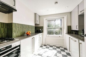 A kitchen with a black and white checkered floor, a window with a view, and a stove. - The Notting Hill Blue Palace (Greater London)