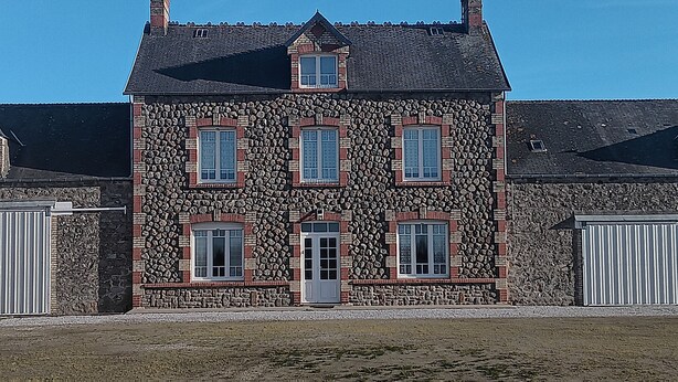 A multi-story building with a stone facade, multiple windows, and a central entrance.