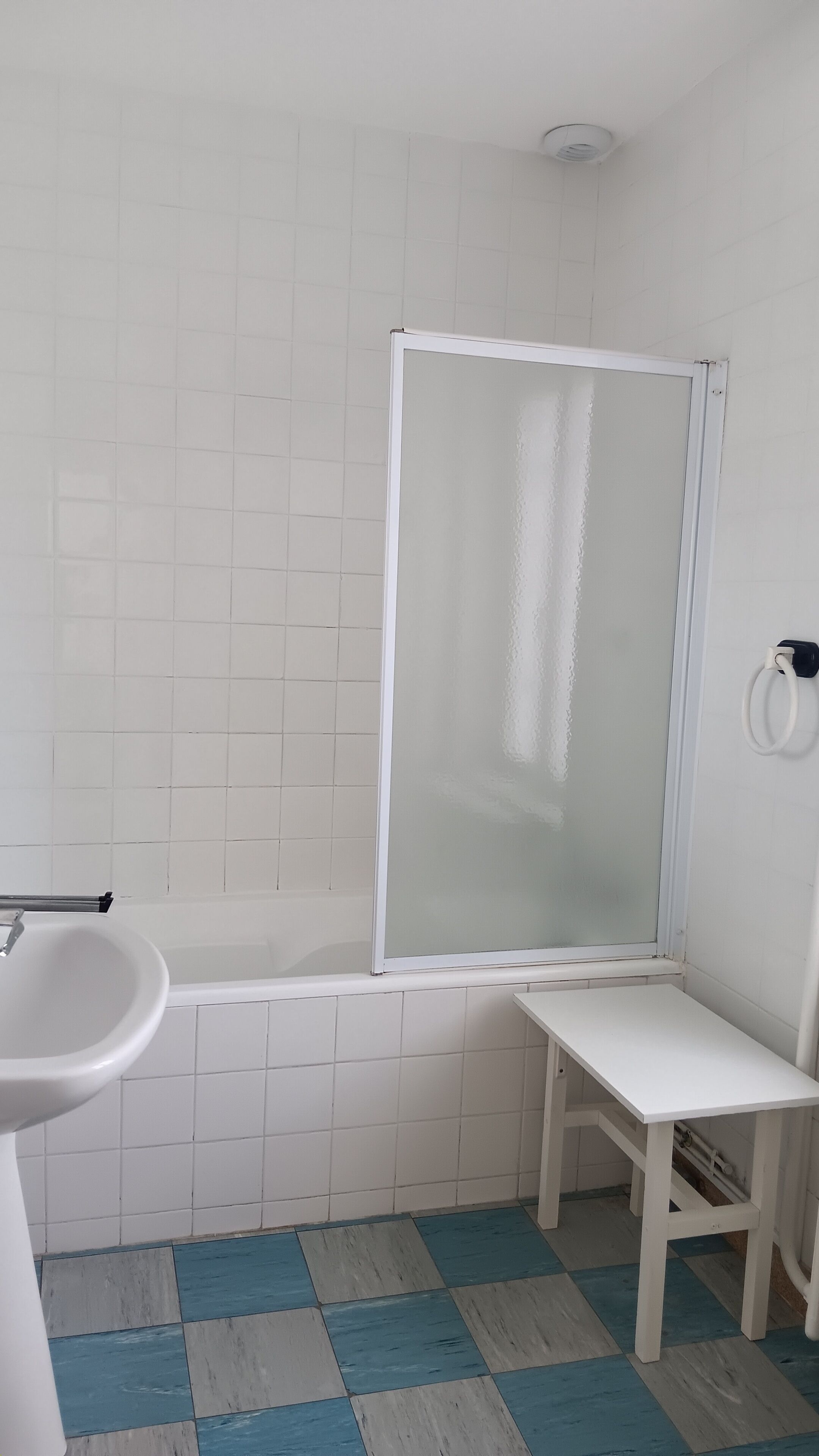 A bathroom with a shower enclosure, a sink, and a bench.
