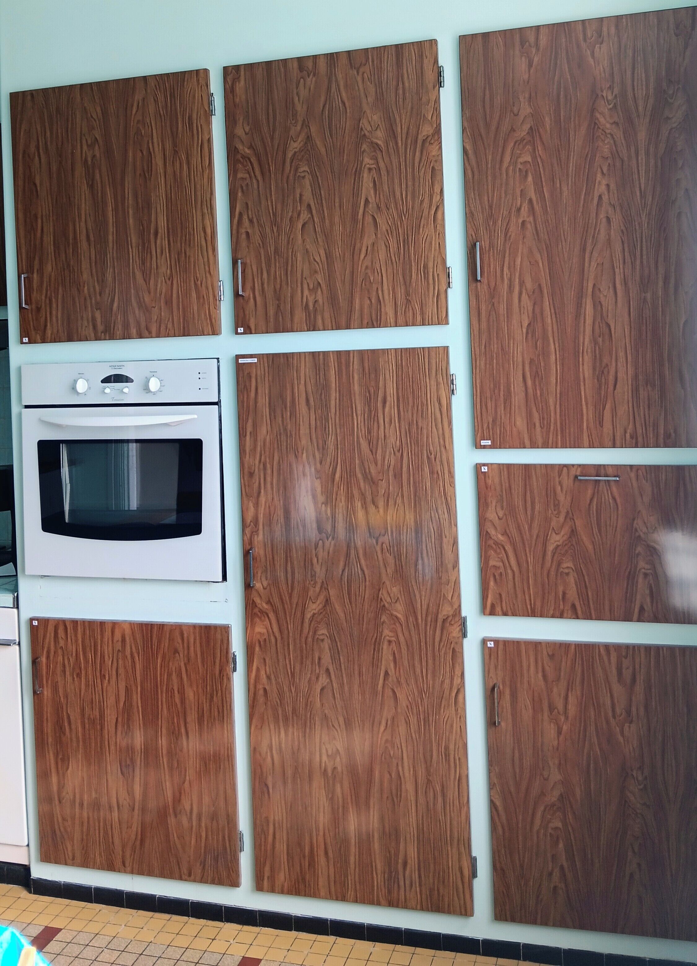 Een keuken met een inbouwoven en kasten met een houtnerfstructuur.