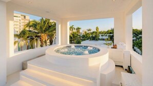 A modern spa area with a hot tub, a staircase, and a view of palm trees and buildings. - Luxury 5BR Villa Jomtien - Pool, Sports & Karaoke Close to the beach of pattaya (เมืองพัทยา)