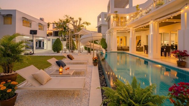 A modern hotel with a pool, lounge chairs, and a slide. - Luxury 5BR Villa Jomtien - Pool, Sports & Karaoke Close to the beach of pattaya (เมืองพัทยา)