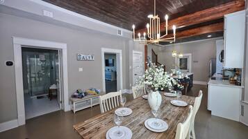 A dining area with a wooden table set for four, a chandelier, and a sign that reads 'STAY'.